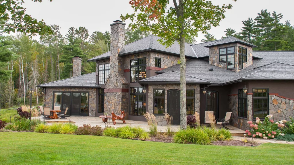 exterior of a stone custom home with patio furniture and landscaping